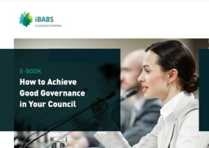 Person speaking into a microphone at a conference. The text reads "E-Book: How to Achieve Good Governance in Your Council," by iBABS, a Euronext Company.